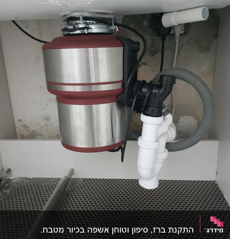 מכשיר טוחן אשפה מותקן מתחת לכיור עם צינורות פלסטיק